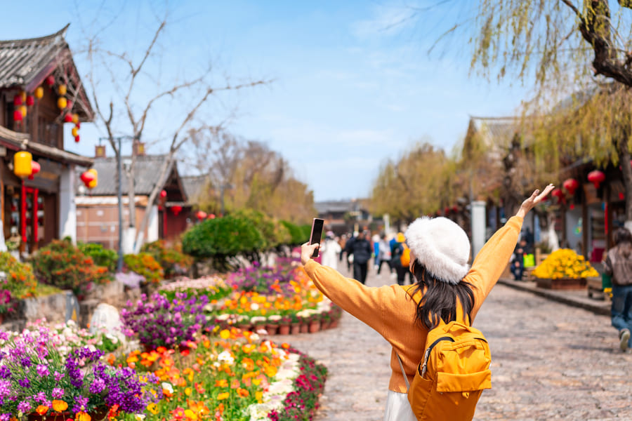 Chica extendiendo los brazos con gardineras de flores al fondo
